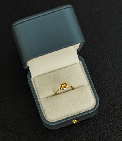 a ring with a yellow gemstone laying in the box