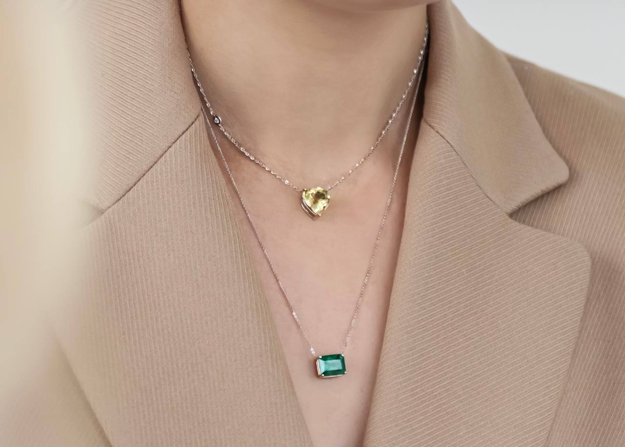 a pendant with a green gemstone and a pendant with a yellow gemstone with a shape of heart