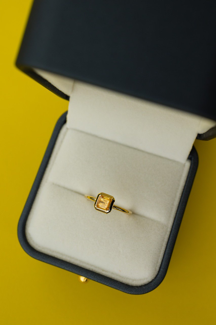 a ring with a yellow gemstone laying in the box