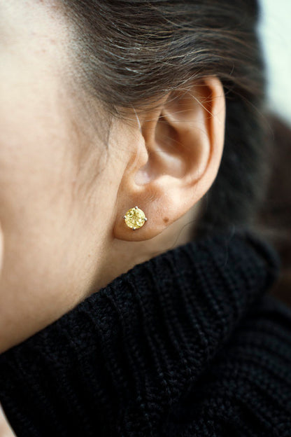 a stud with a yellow gemstone in the ear