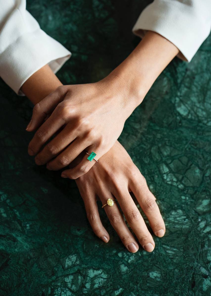 a ring with a green gemstone and a ring with a yellow gemstone